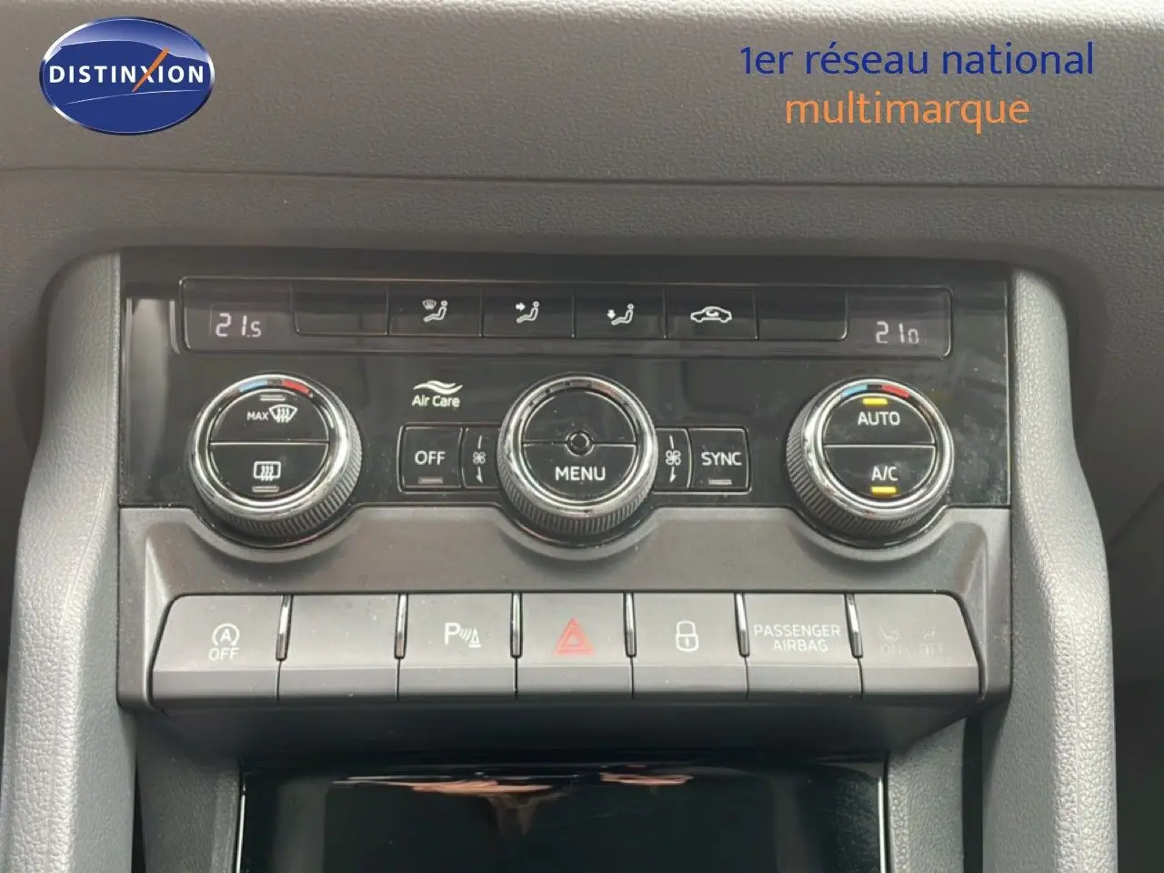 Vue rapprochée de la console centrale du Skoda Karoq blanc glacier, mettant en valeur les commandes de climatisation et boutons fonctionnels.