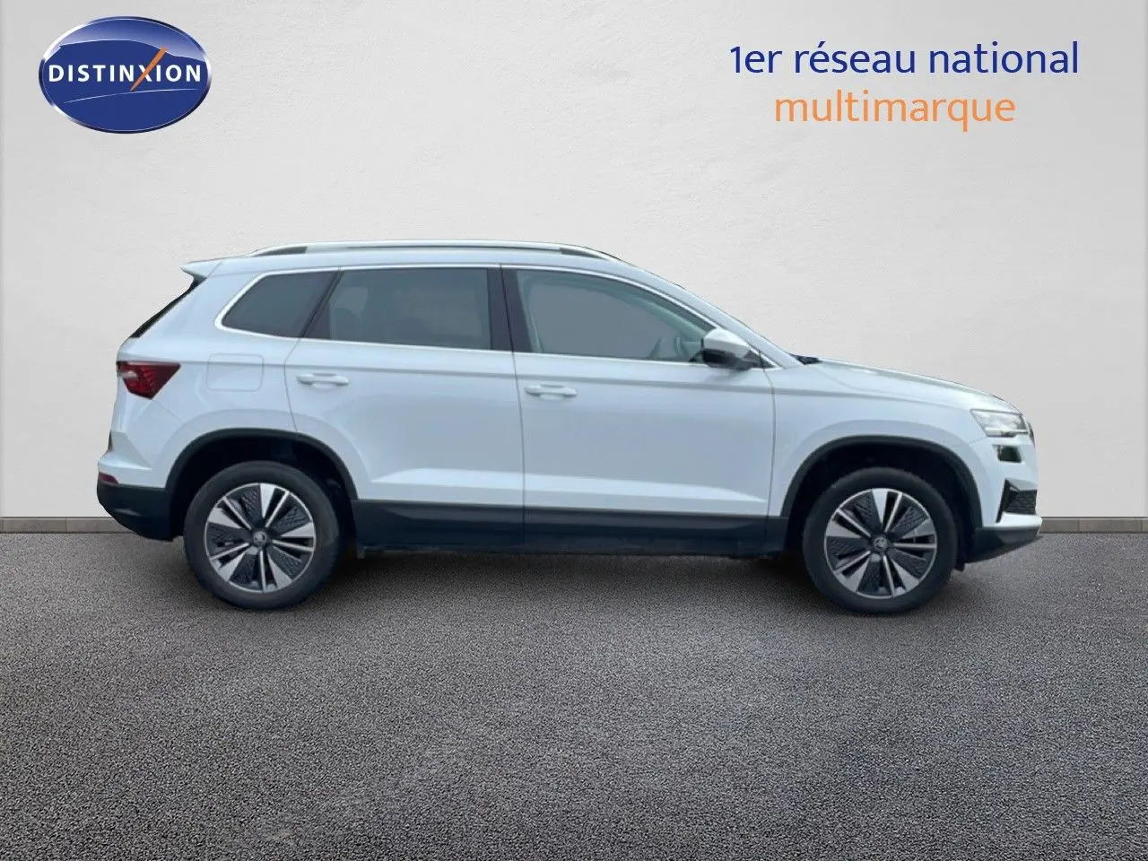 Vue profil droit d’un Skoda Karoq blanc glacier 2025 avec jantes alliage et barres de toit noires.