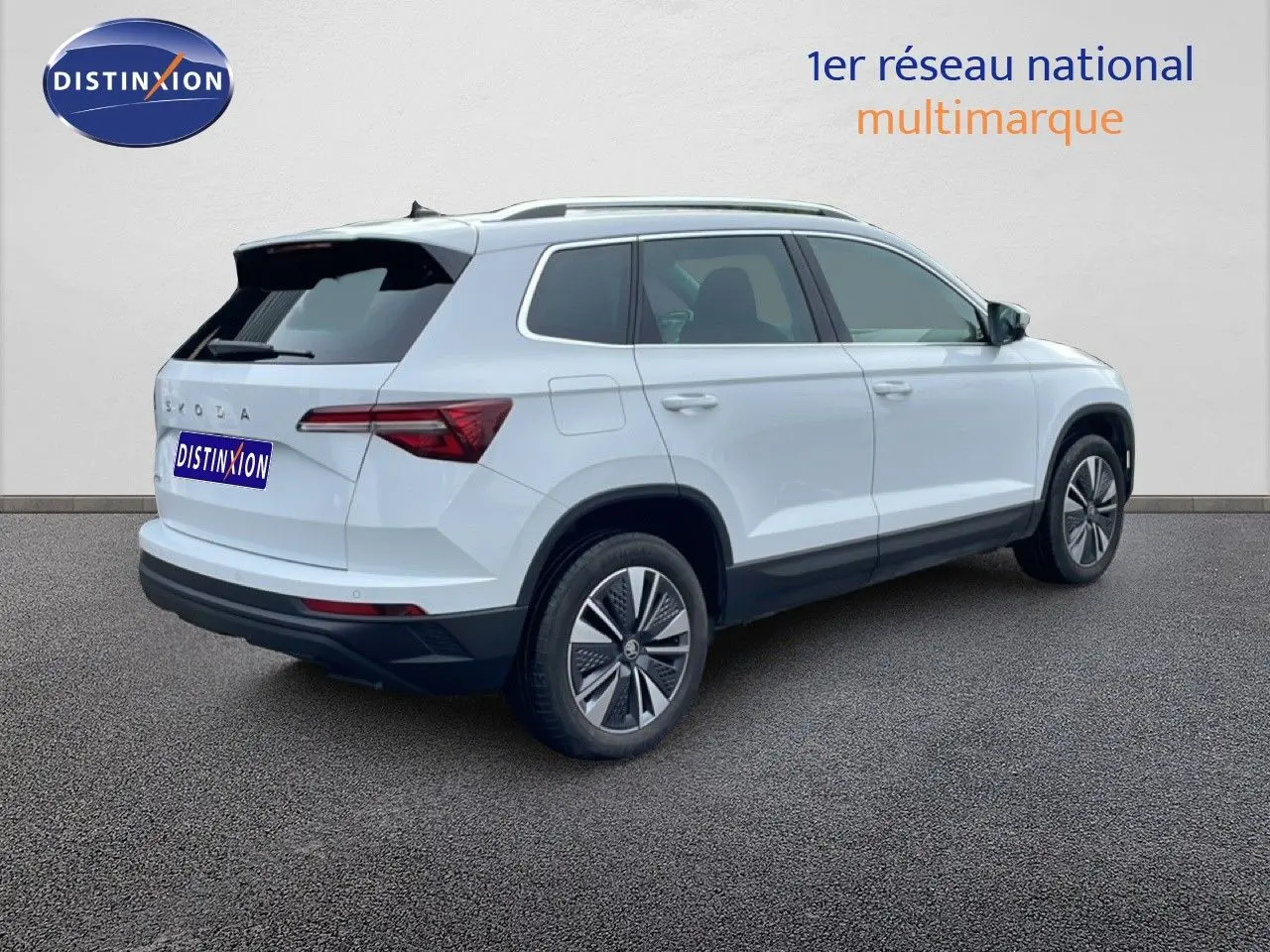 Vue 3/4 arrière droite d'un Skoda Karoq blanc glacier 2025 avec jantes bi-ton et feux arrière LED distinctifs.