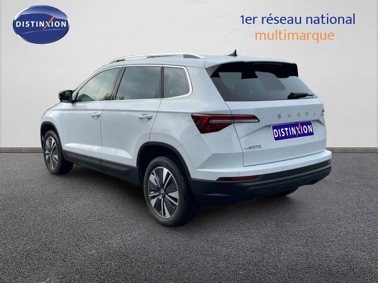 Vue 3/4 arrière droite d’un Skoda Karoq blanc glacier avec jantes bi-ton et vitres teintées.