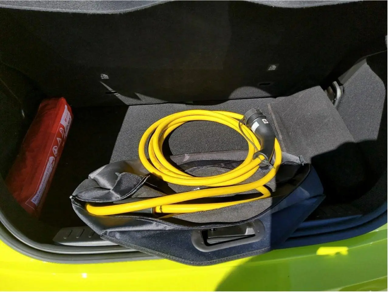 Coffre ouvert d’une FIAT 500 Electrique Jaune Acid avec câble de recharge jaune enroulé visible.