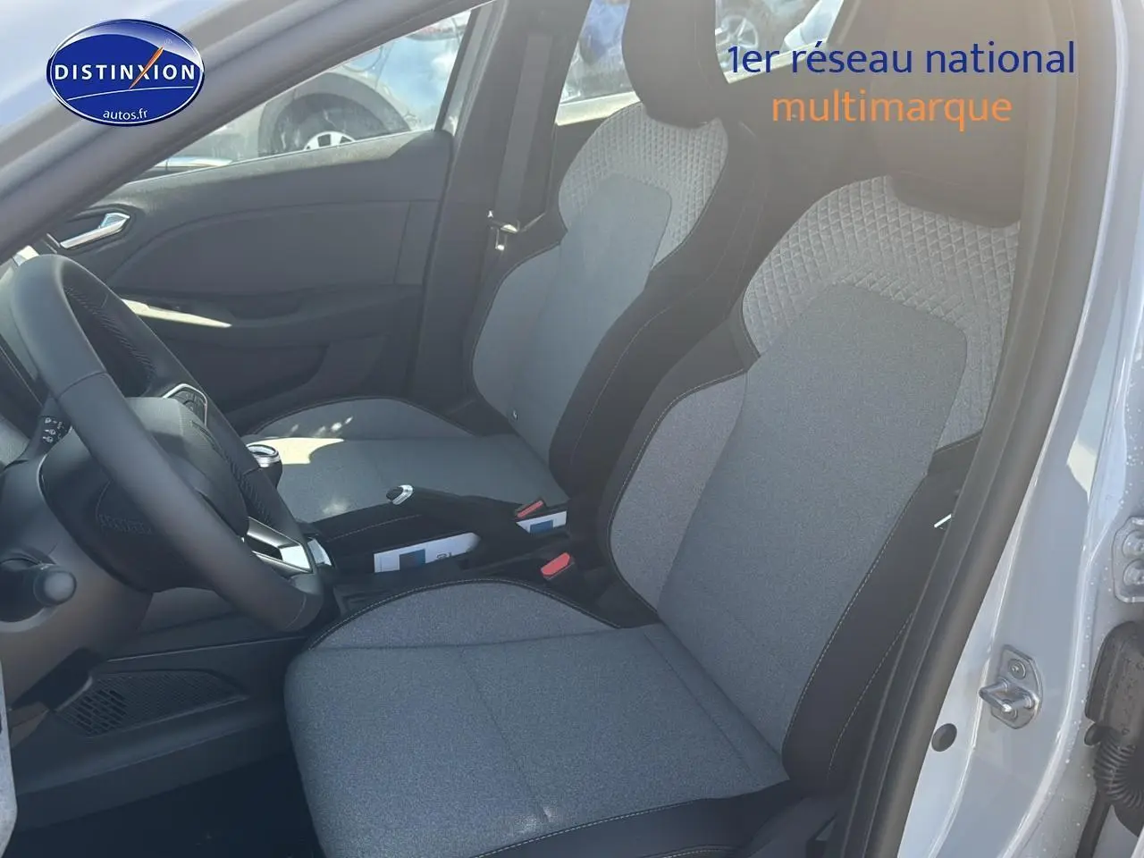 Vue intérieure côté conducteur de la Renault Clio V 1.5 dCi 100 gris rafale, sièges tissu gris et volant cuir.