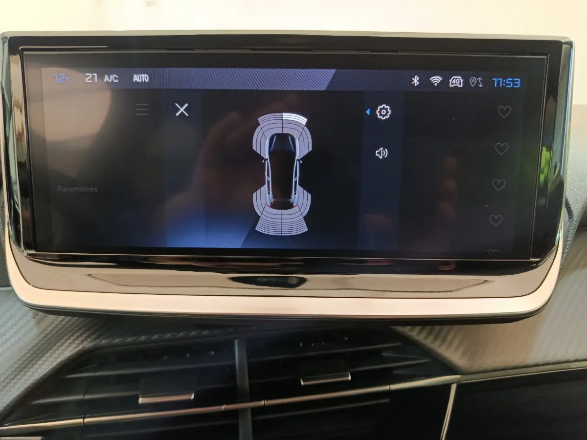 Écran tactile central affichant l'aide au stationnement de la Peugeot 208 gris clair, vue intérieure rapprochée