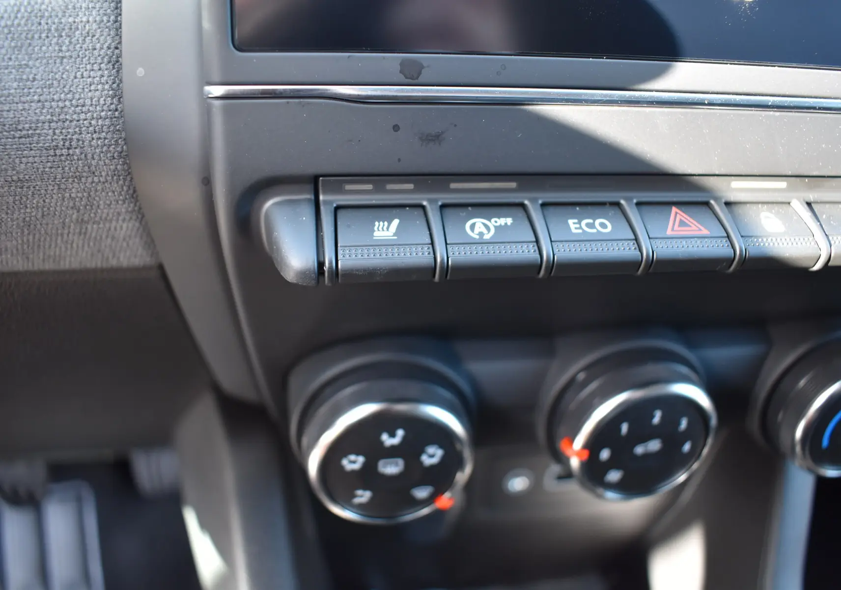 Gros plan sur la console centrale de la Renault Clio V noire 2025, montrant les commandes de climatisation et boutons fonctionnels.