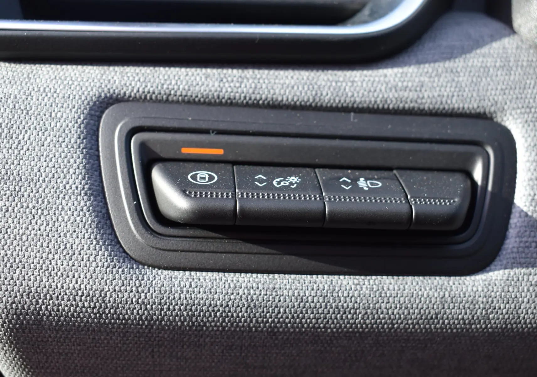 Gros plan sur les boutons de réglage d’éclairage et verrouillage de la Renault Clio V TCe 90 noire, intérieur tissu gris.