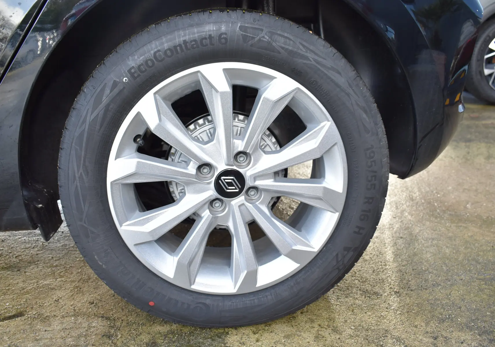 Gros plan sur la roue avant gauche d'une Renault Clio V noire, mettant en valeur la jante argentée au design moderne.