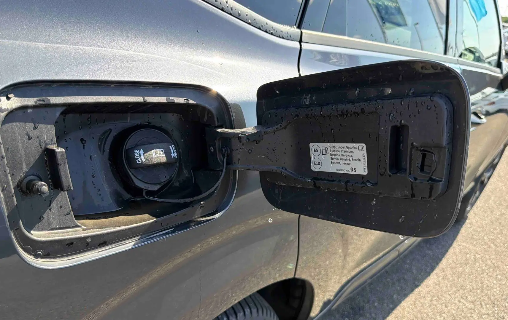 Trappe de carburant ouverte côté gauche d'une CUPRA TERRAMAR grise sous lumière naturelle.