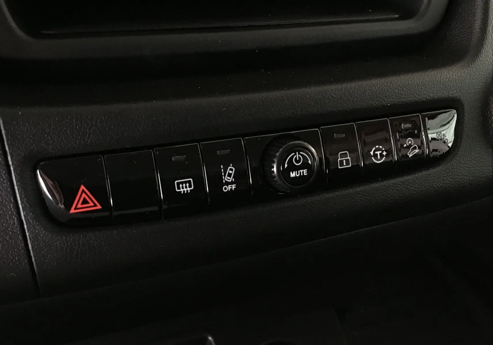 Gros plan sur la rangée de boutons de commande noirs avec symbole d'alerte rouge dans l'habitacle du Peugeot Boxer Fourgon blanc.