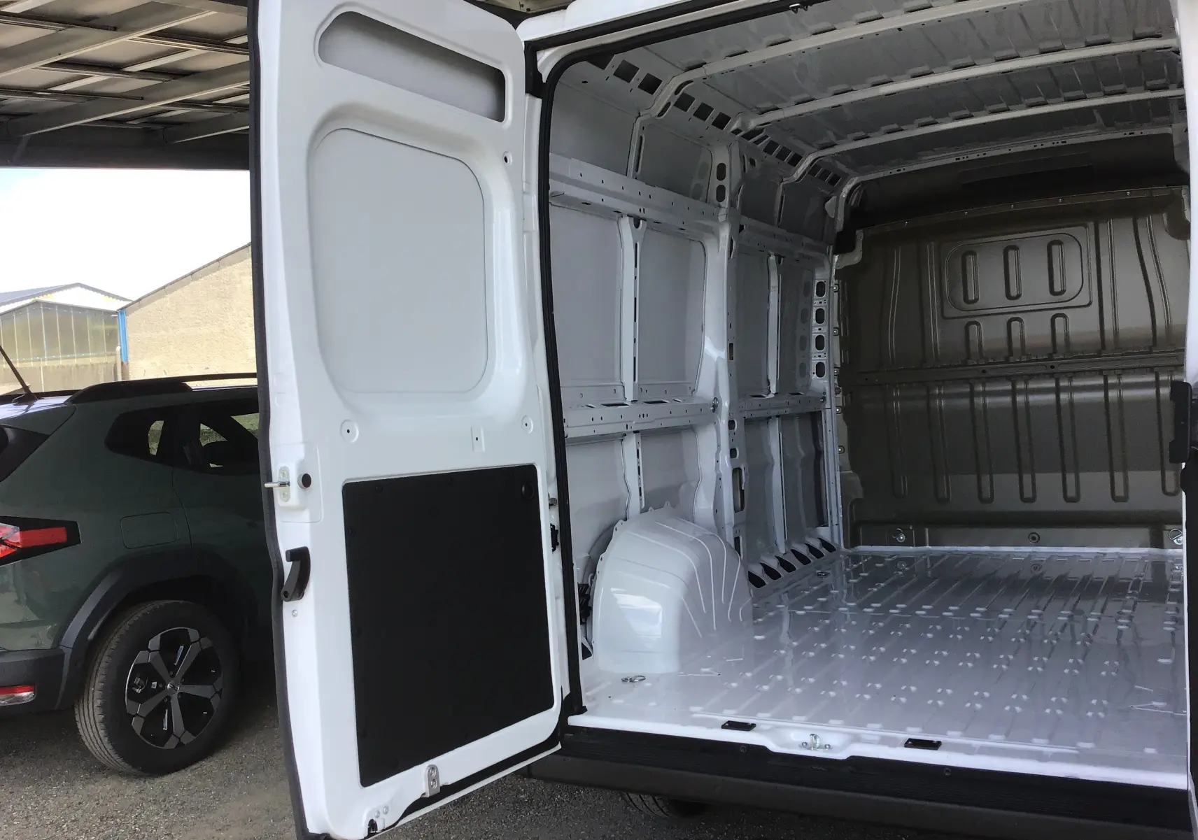 Vue arrière ouverte du Peugeot Boxer Fourgon blanc 2025 montrant l'intérieur vide et la structure métallique du coffre.