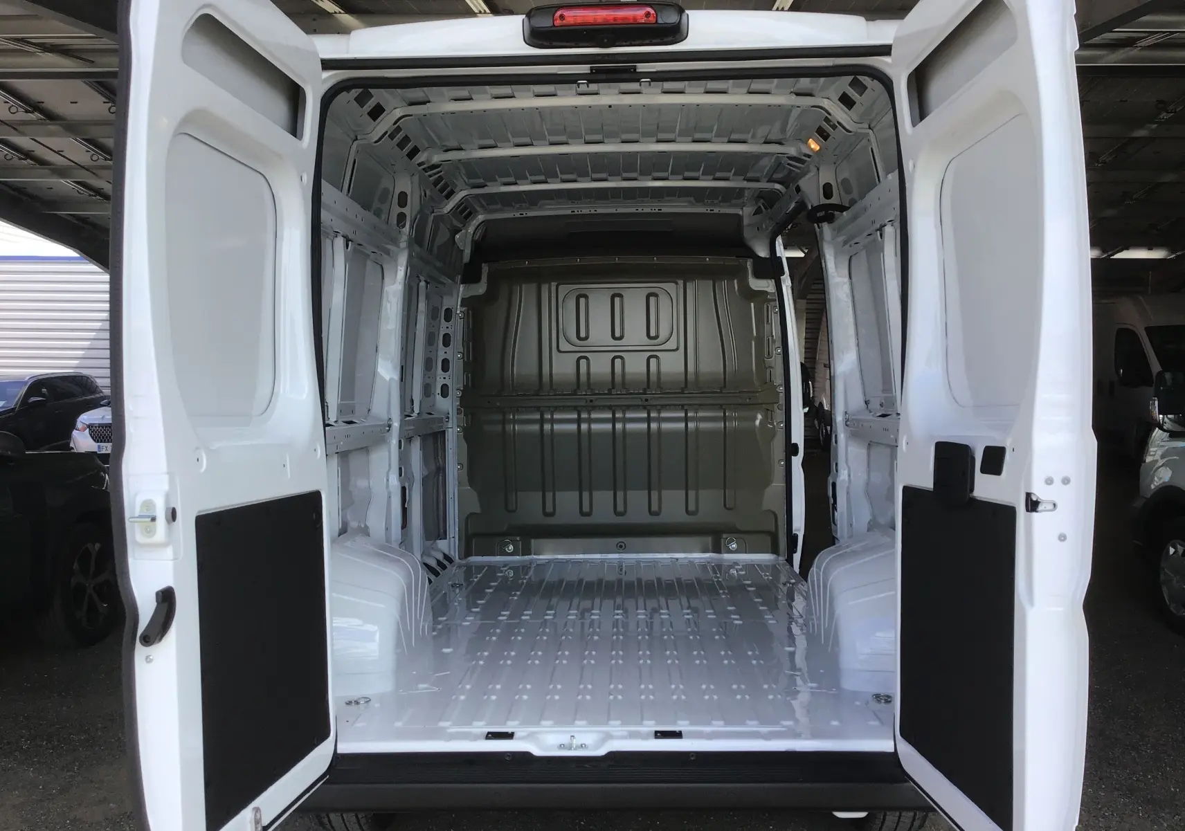 Vue arrière du Peugeot Boxer Fourgon blanc 2025 avec portes ouvertes montrant l'espace de chargement vide et métallique.