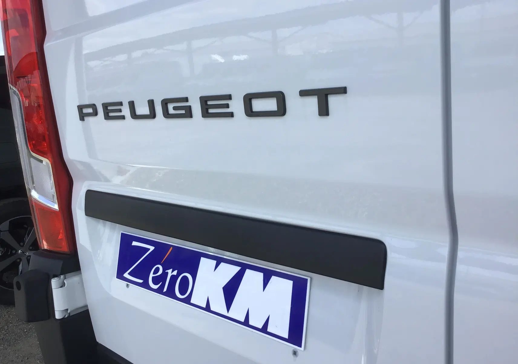 Gros plan sur l'arrière blanc du Peugeot Boxer Fourgon avec logo et plaque d'immatriculation Zero KM visible.