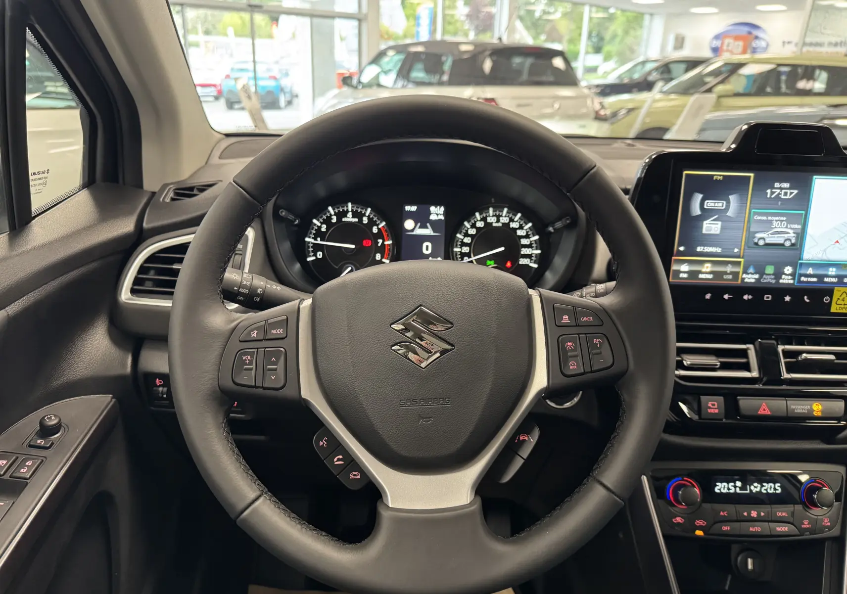 Vue intérieure centrée sur le volant noir du Suzuki S-Cross 1.4 Hybrid 2025 avec tableau de bord et écran tactile.