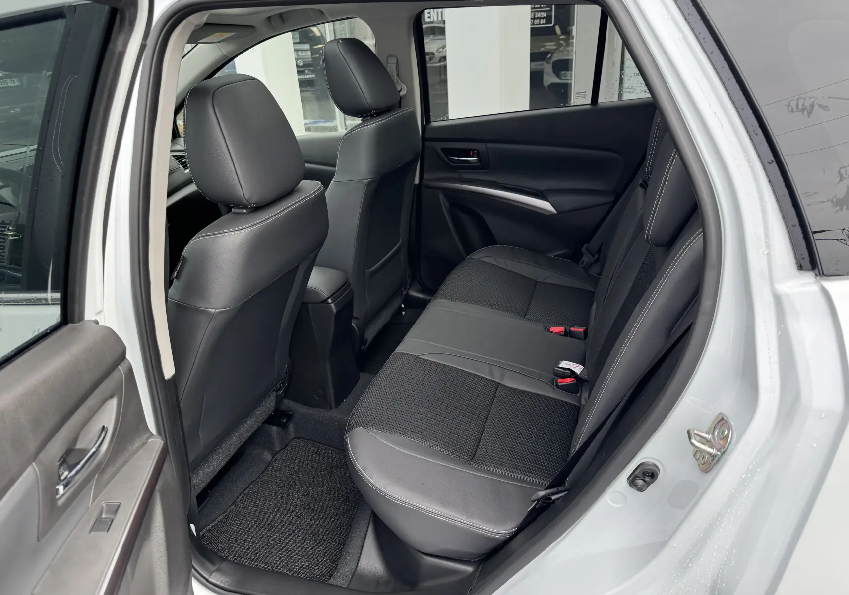 Vue intérieure côté gauche des sièges arrière en cuir noir du Suzuki S-Cross blanc 2025, avec porte ouverte.