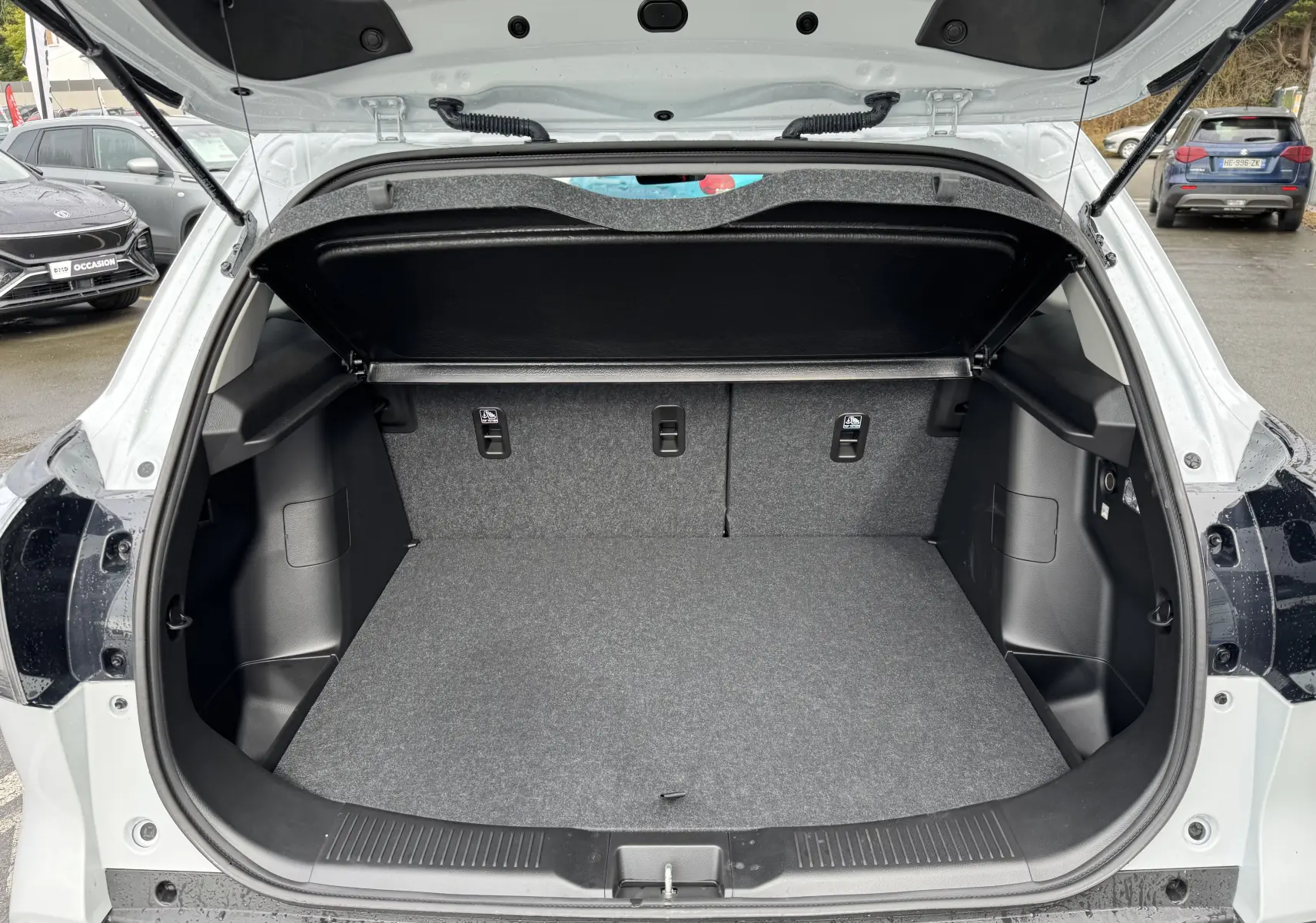 Coffre ouvert vu de l'arrière d'un Suzuki S-Cross blanc 2025, montrant un espace de chargement propre et spacieux.