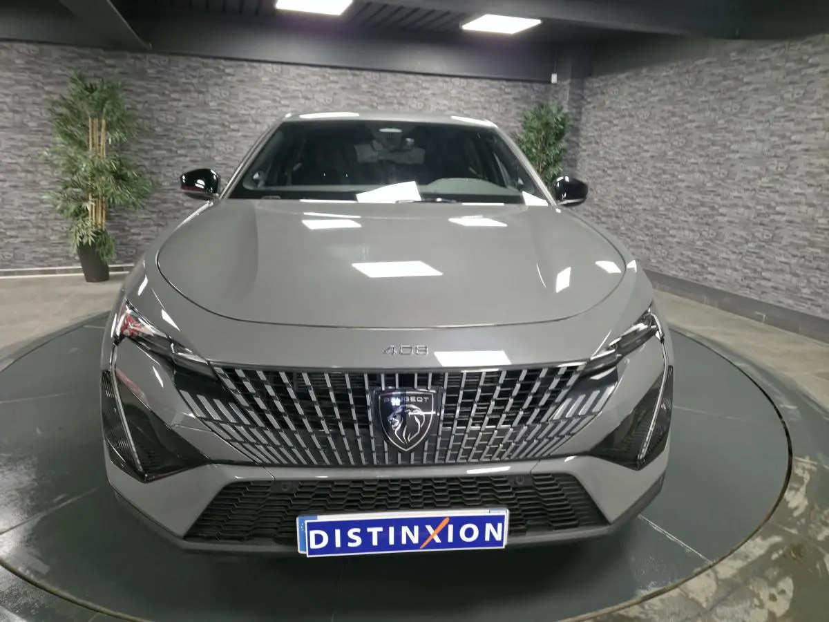 Vue avant centrée d'une Peugeot 408 gris métallisé avec calandre verticale et logo lion distinctif.