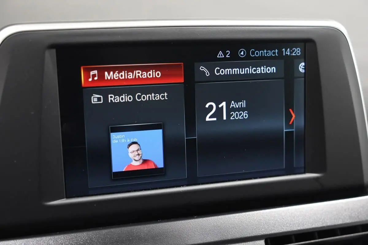Écran central de la BMW Série 2 Active Tourer 216d blanc affichant les menus Média/Radio et Communication avec date du 21 avril 2026.