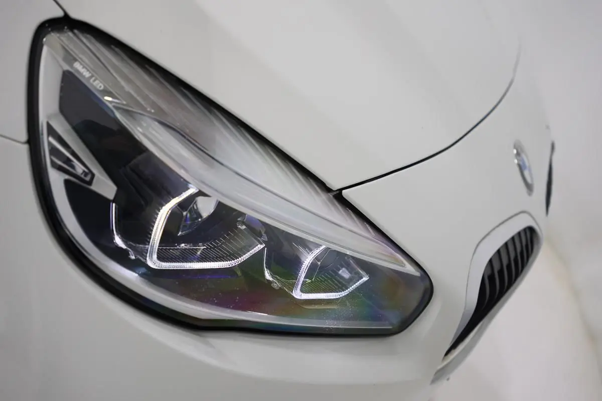 Gros plan sur le phare avant gauche blanc d'une BMW Série 2 Active Tourer 216d avec calandre caractéristique.