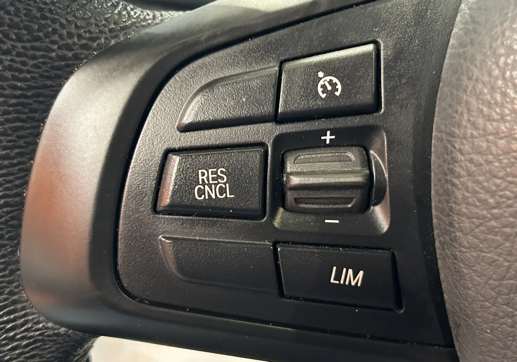 Gros plan sur les commandes de régulateur de vitesse au volant noir du BMW Série 2 Active Tourer blanc.