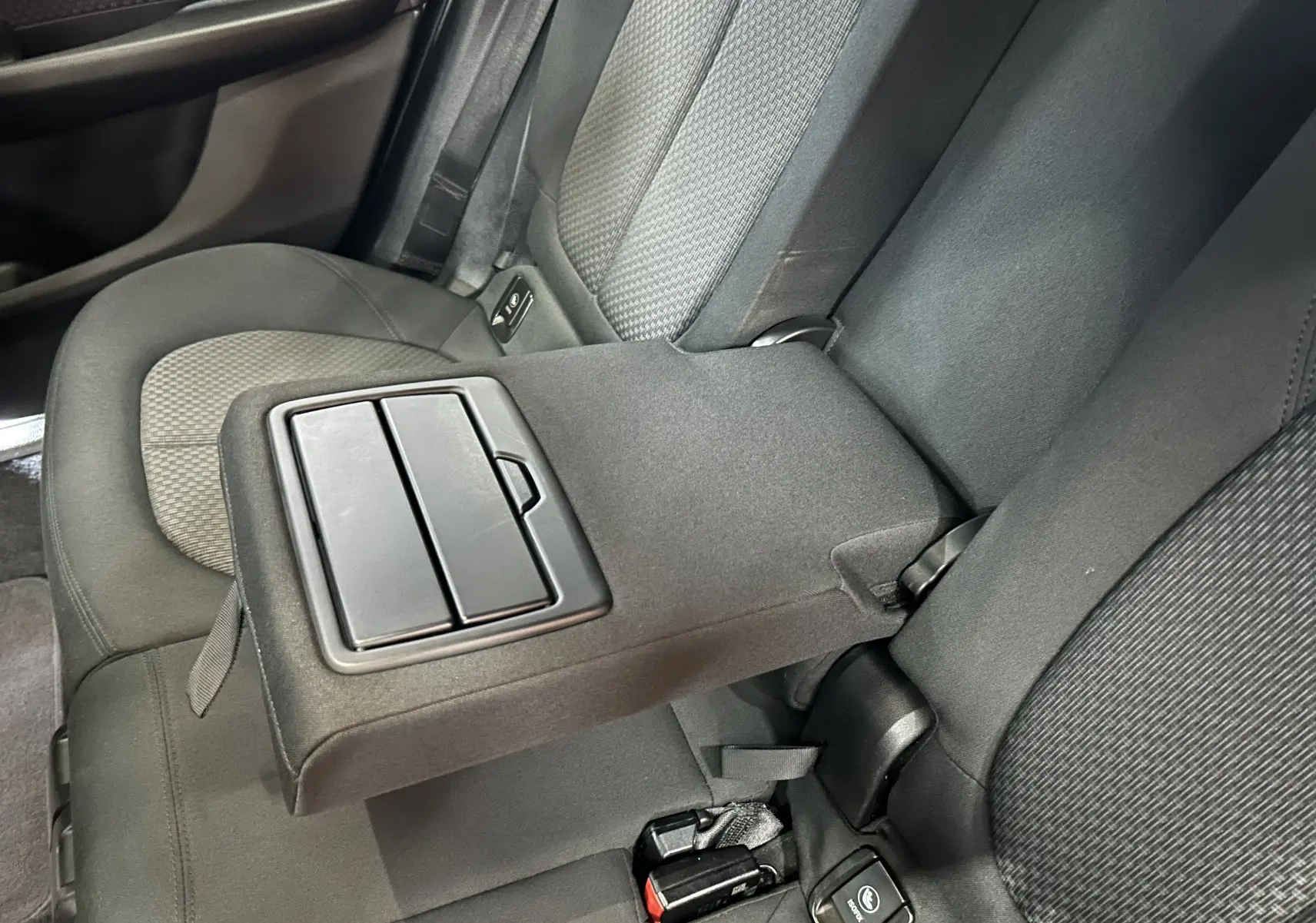 Détail de l'accoudoir central arrière en tissu gris dans l'habitacle d'une BMW Série 2 Active Tourer blanche.
