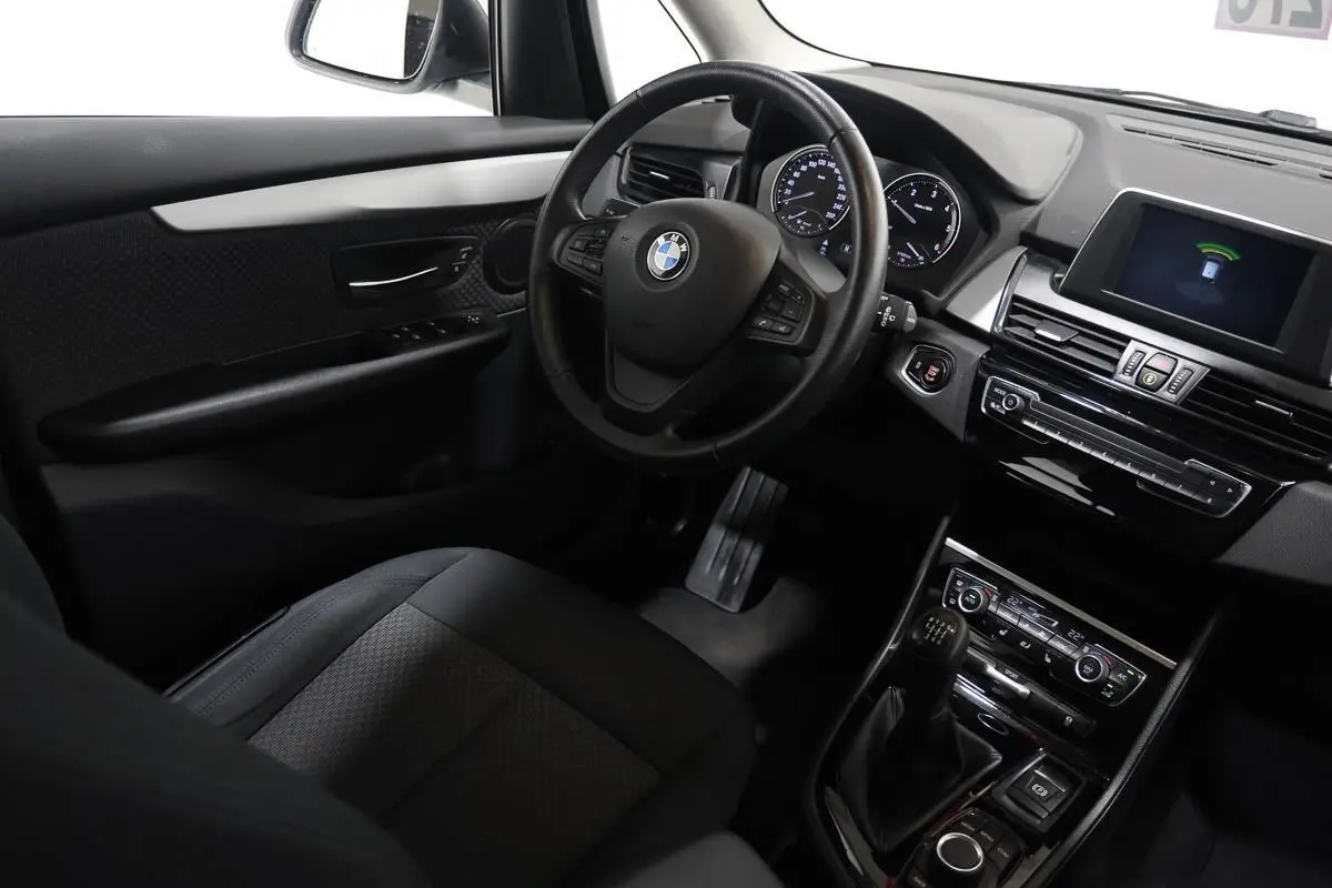 Vue intérieure côté conducteur de la BMW Série 2 Active Tourer blanche, avec volant cuir et boîte manuelle visible.