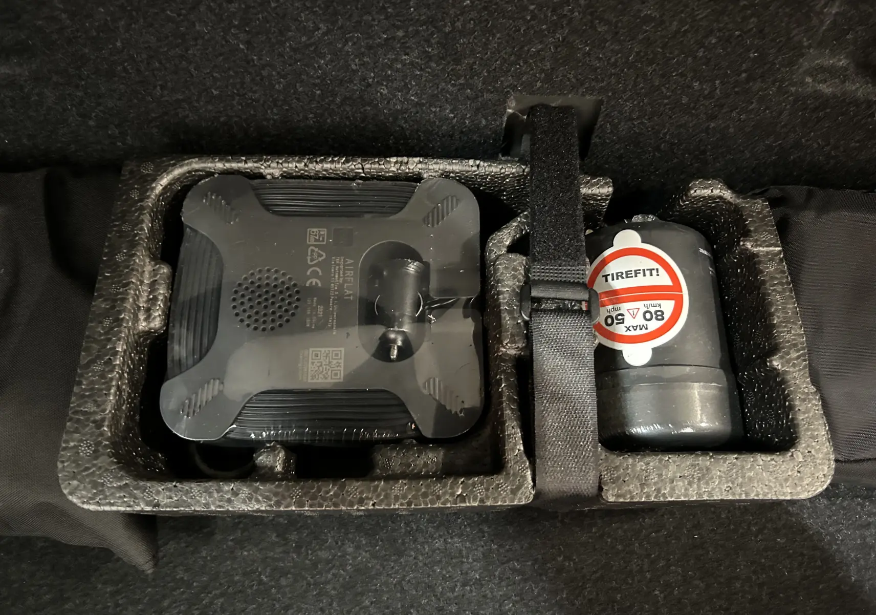 Kit de réparation de pneu avec compresseur et produit d'étanchéité dans le coffre d'une BMW Série 2 Active Tourer blanche.
