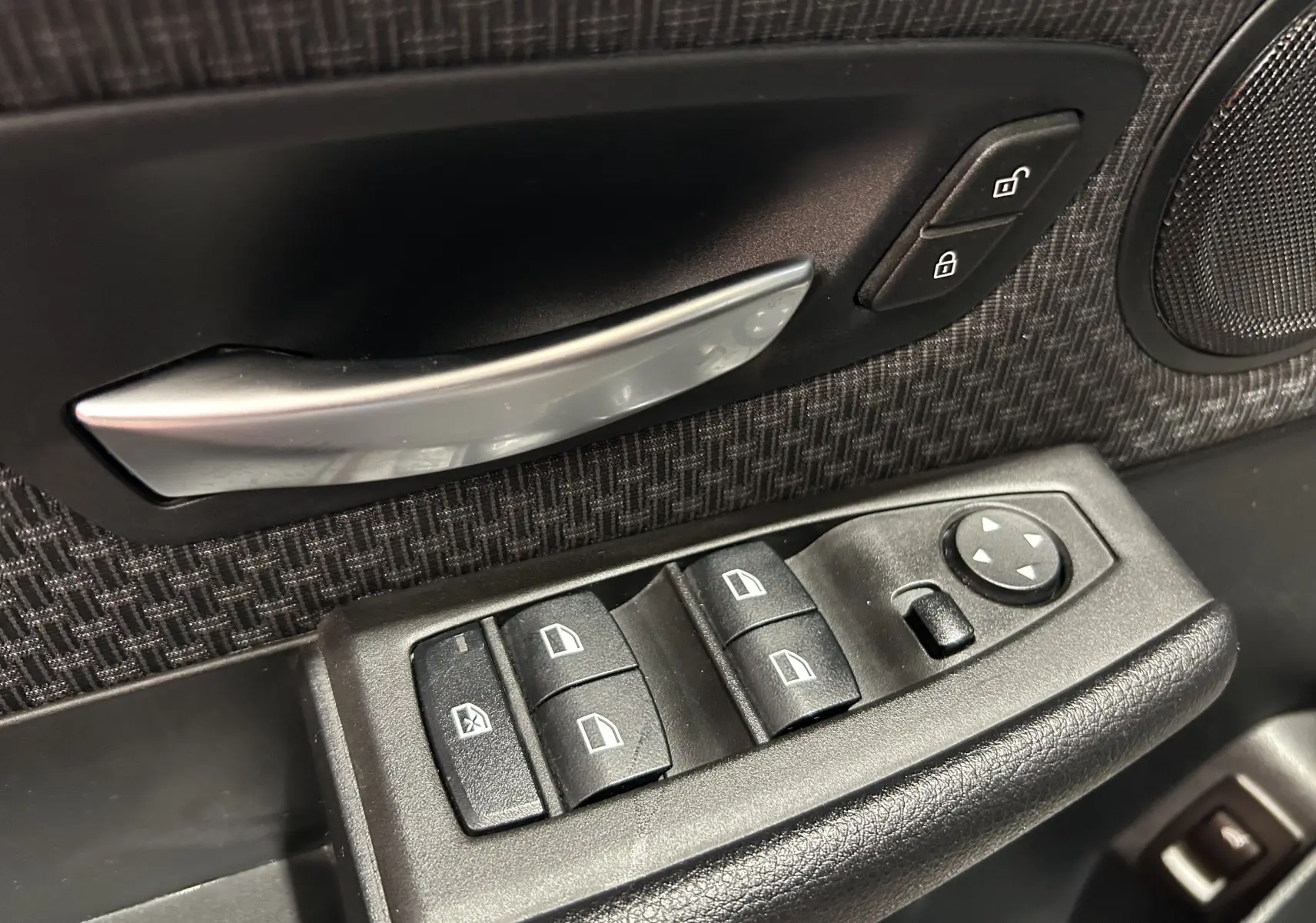 Gros plan sur la commande de lève-vitres et la poignée intérieure côté conducteur d’une BMW Série 2 Active Tourer 216d blanche.