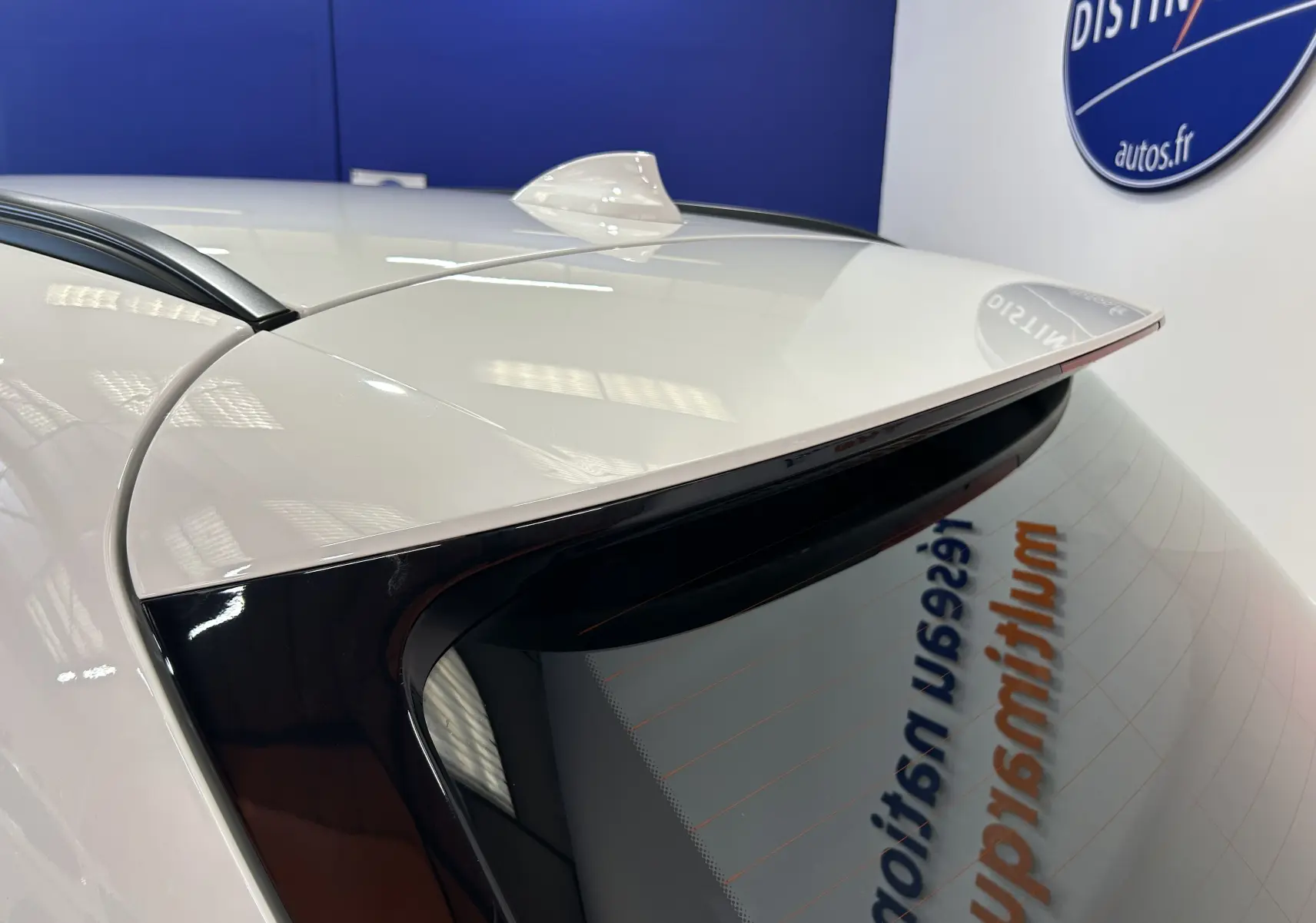 Gros plan sur l’angle arrière droit d’une BMW Série 2 Active Tourer blanche, avec antenne requin et toit ouvrant visible.
