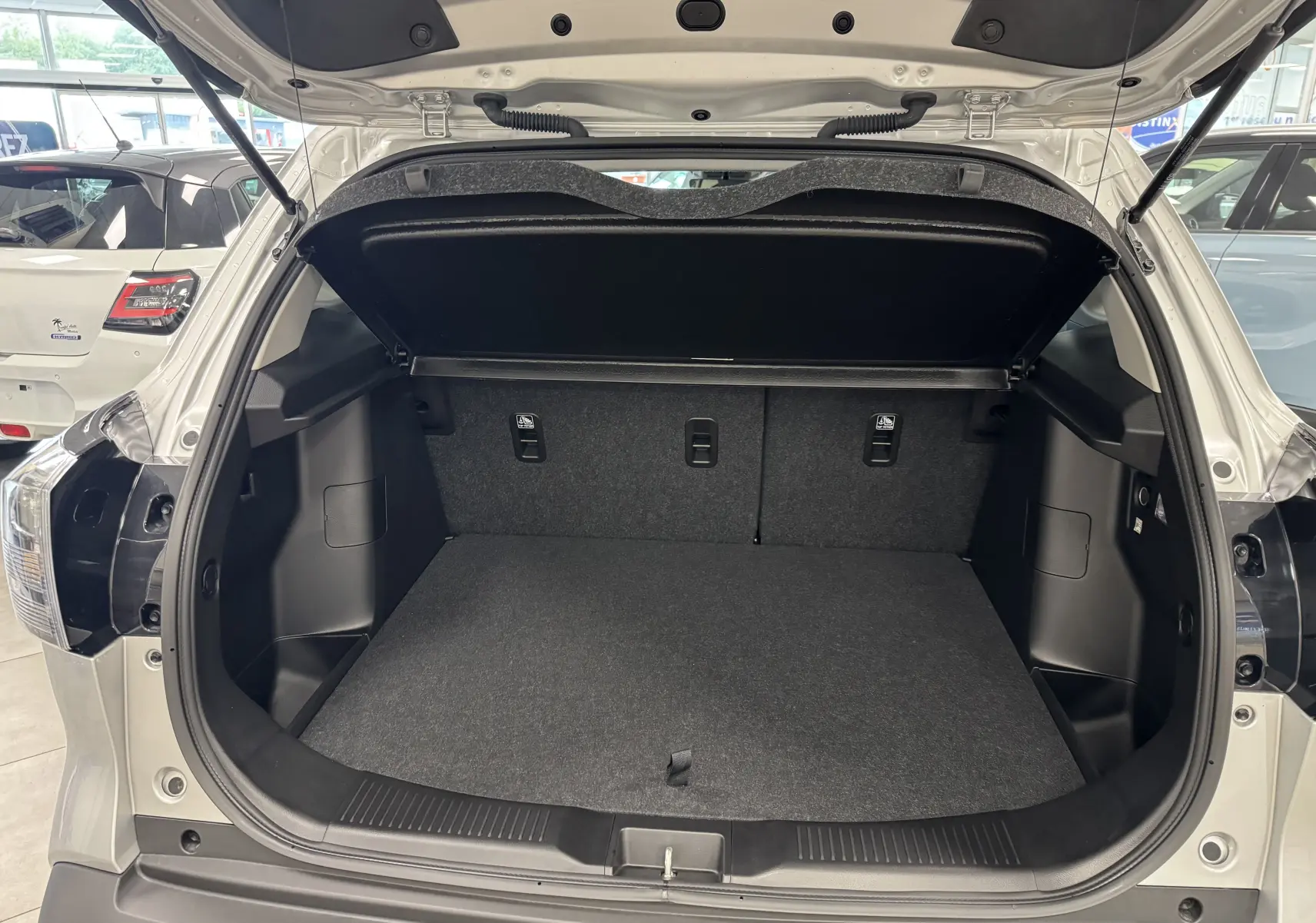 Coffre ouvert vu de l'arrière d'un Suzuki S-Cross gris 2025, montrant un espace de chargement propre et spacieux.
