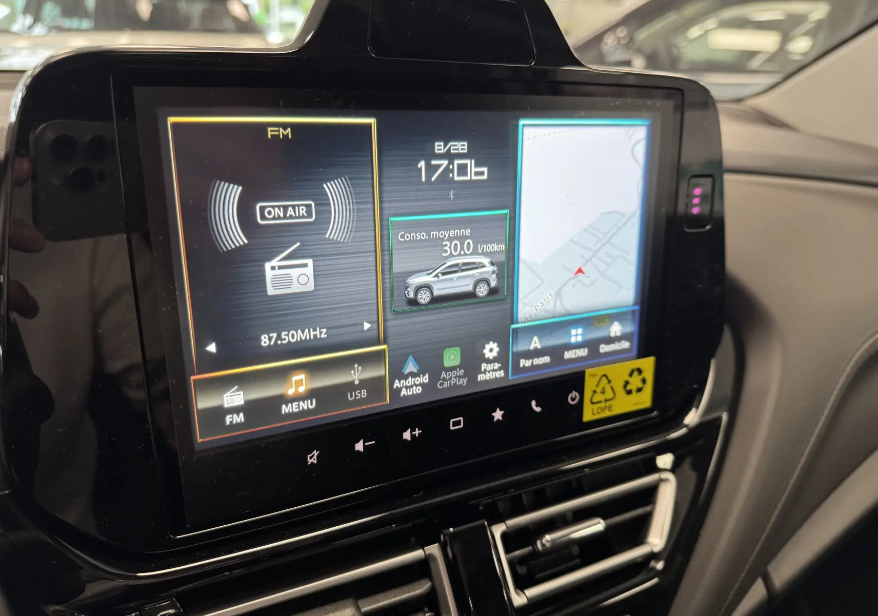 Écran tactile central du Suzuki S-Cross 2025 affichant radio FM, consommation moyenne et navigation GPS.