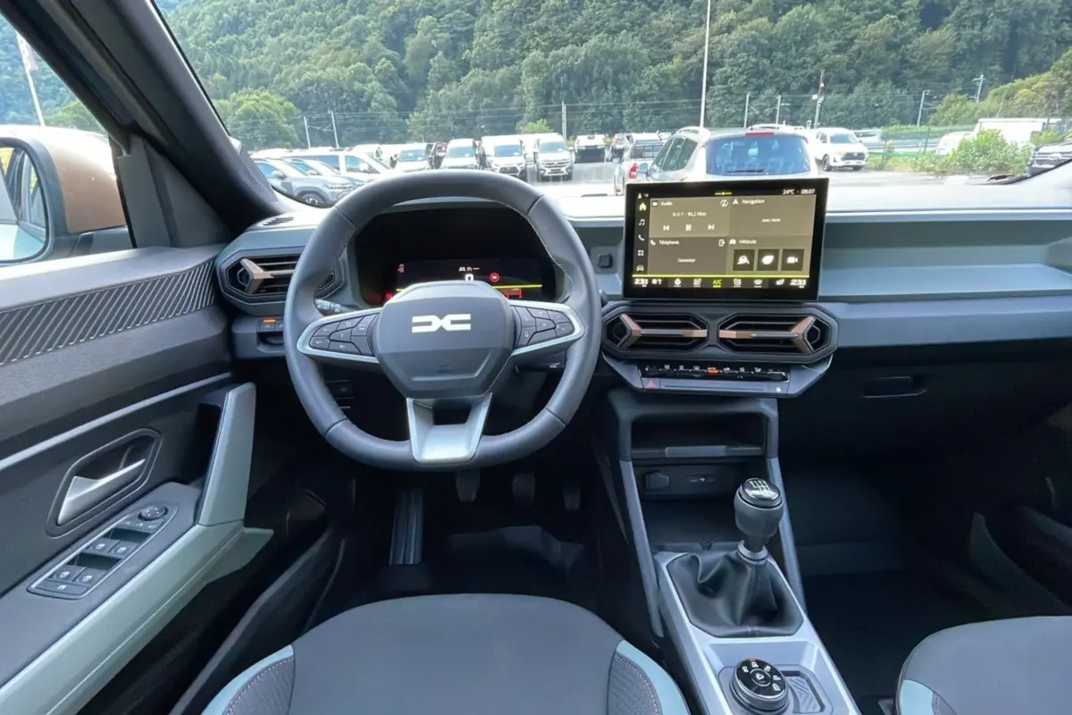 Intérieur du Dacia Bigster TCE 130 4x4 Extreme Plus 2025, vue du poste de conduite avec volant, écran tactile et levier de vitesses manuel.