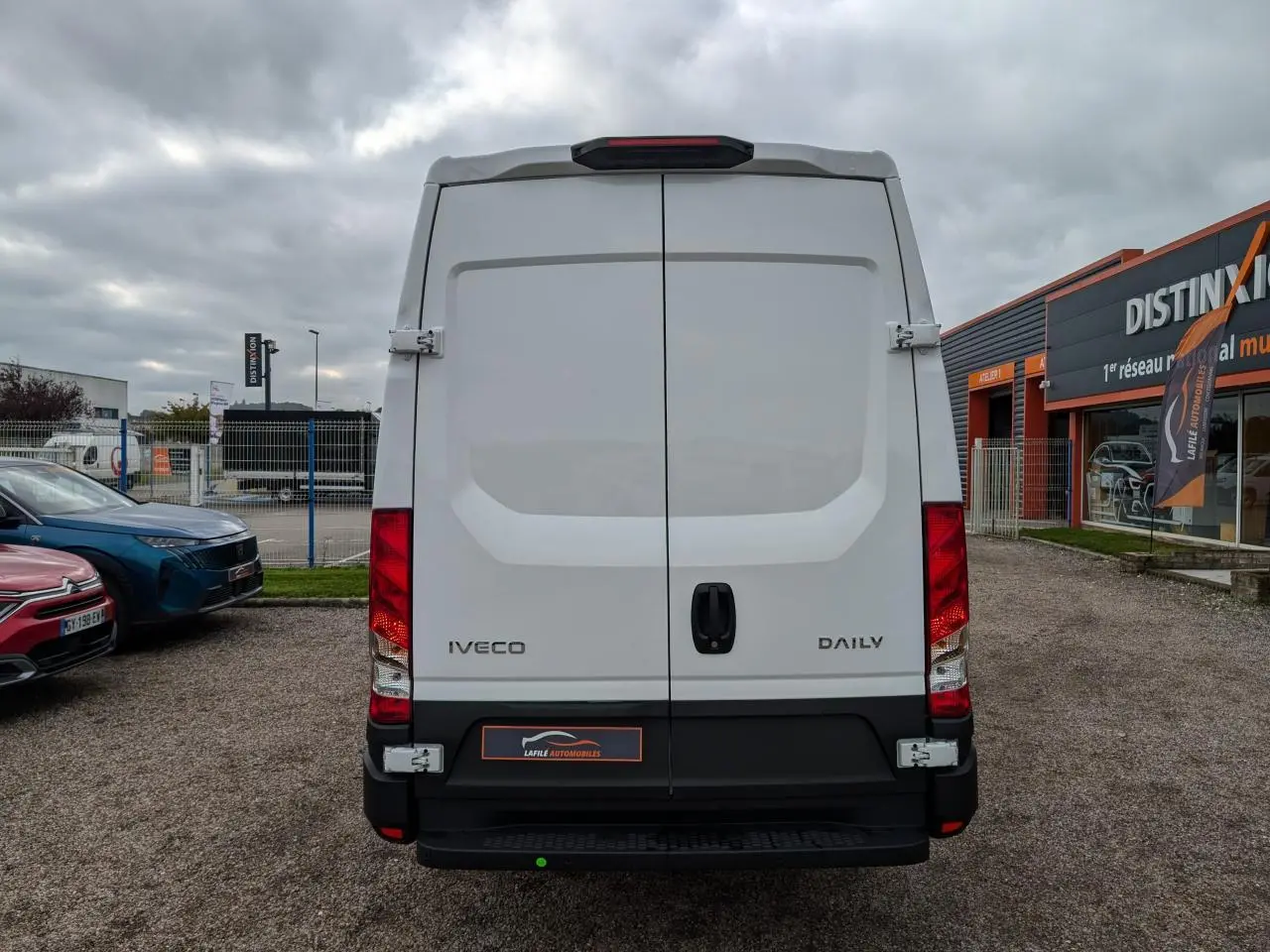 Vue arrière d'un utilitaire blanc Iveco Daily 35S16 avec portes battantes et feux rouges verticaux.