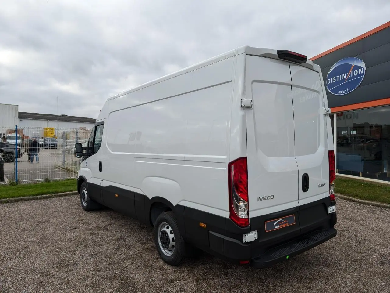 IVECO Daily blanc en vue 3/4 arrière droit, portes arrière doubles et pare-chocs noir visible.