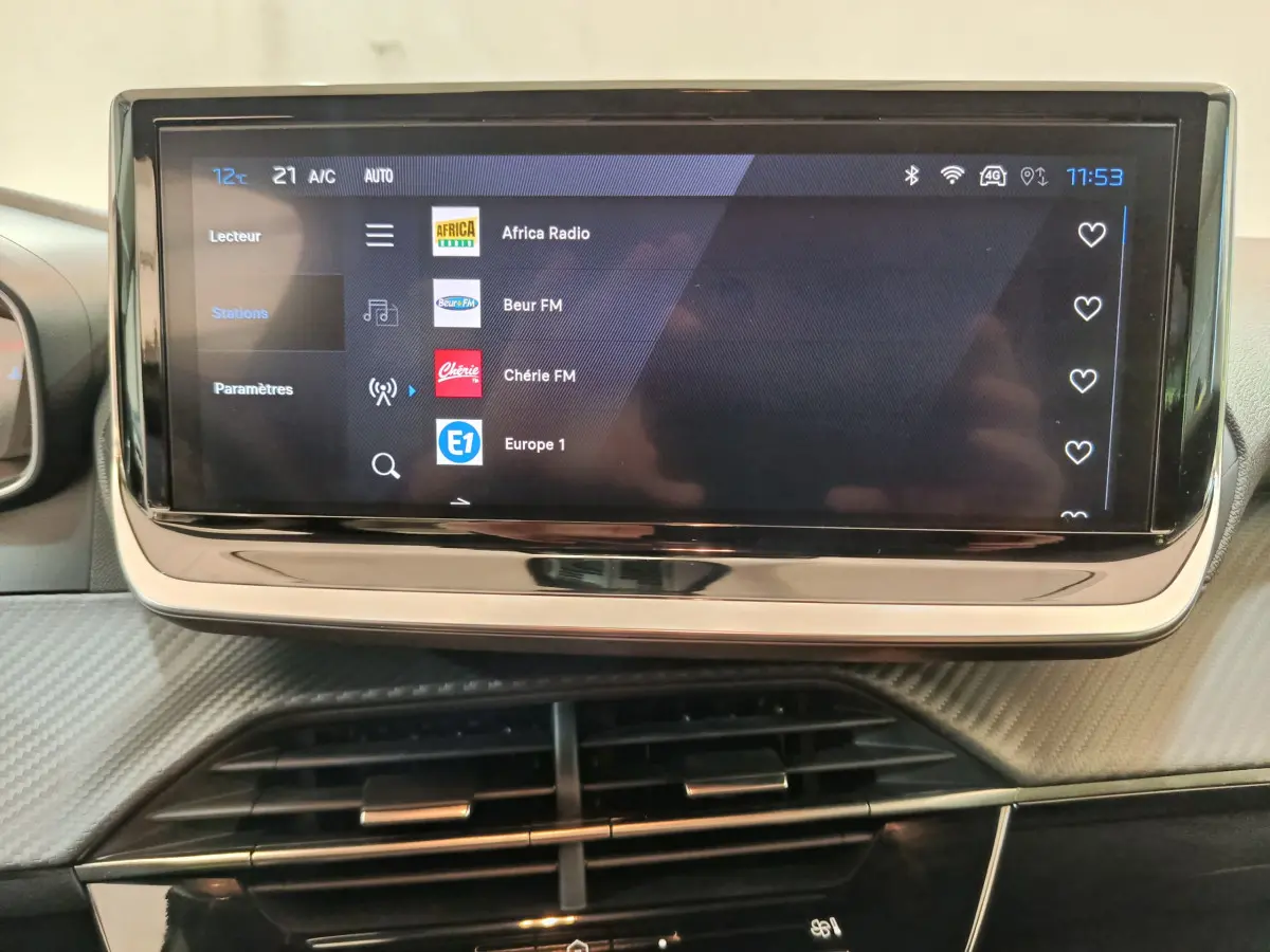 Écran tactile central 10 pouces affichant les stations radio dans l'habitacle de la Peugeot 208 gris clair.