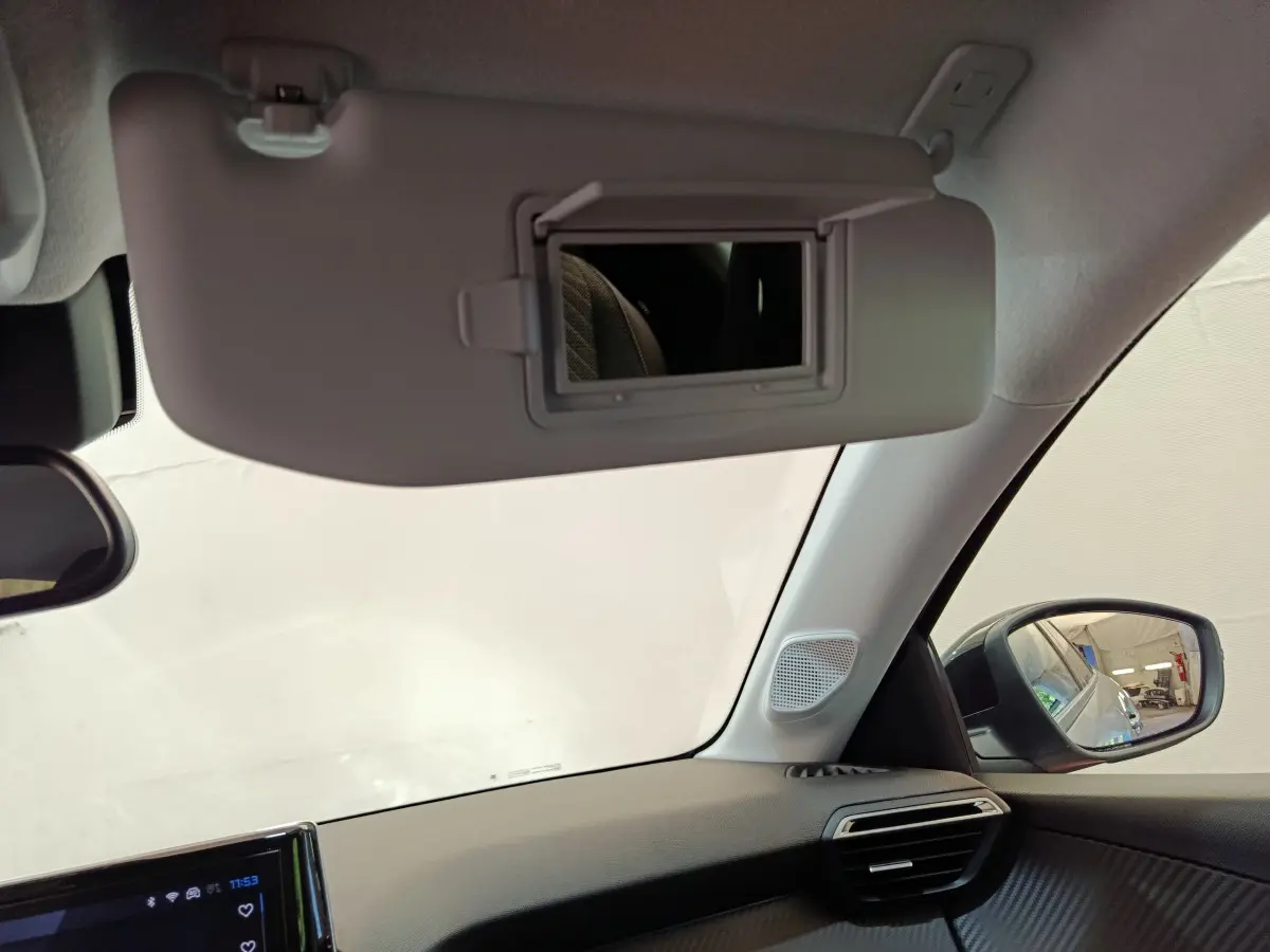 Détail du pare-soleil avec miroir ouvert côté conducteur dans l'habitacle gris clair du Peugeot 208 2025.