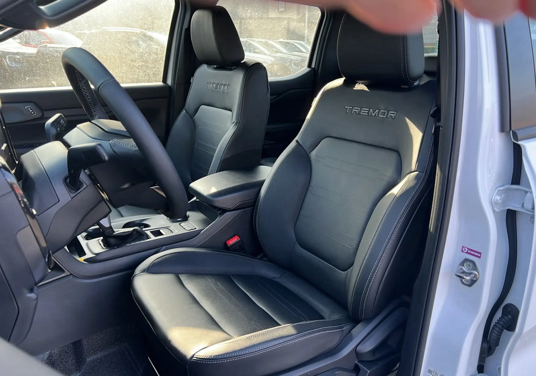 Vue intérieure côté conducteur du Ford Ranger 2025 blanc glacier, sièges cuir noirs avec logo Tremor brodé.