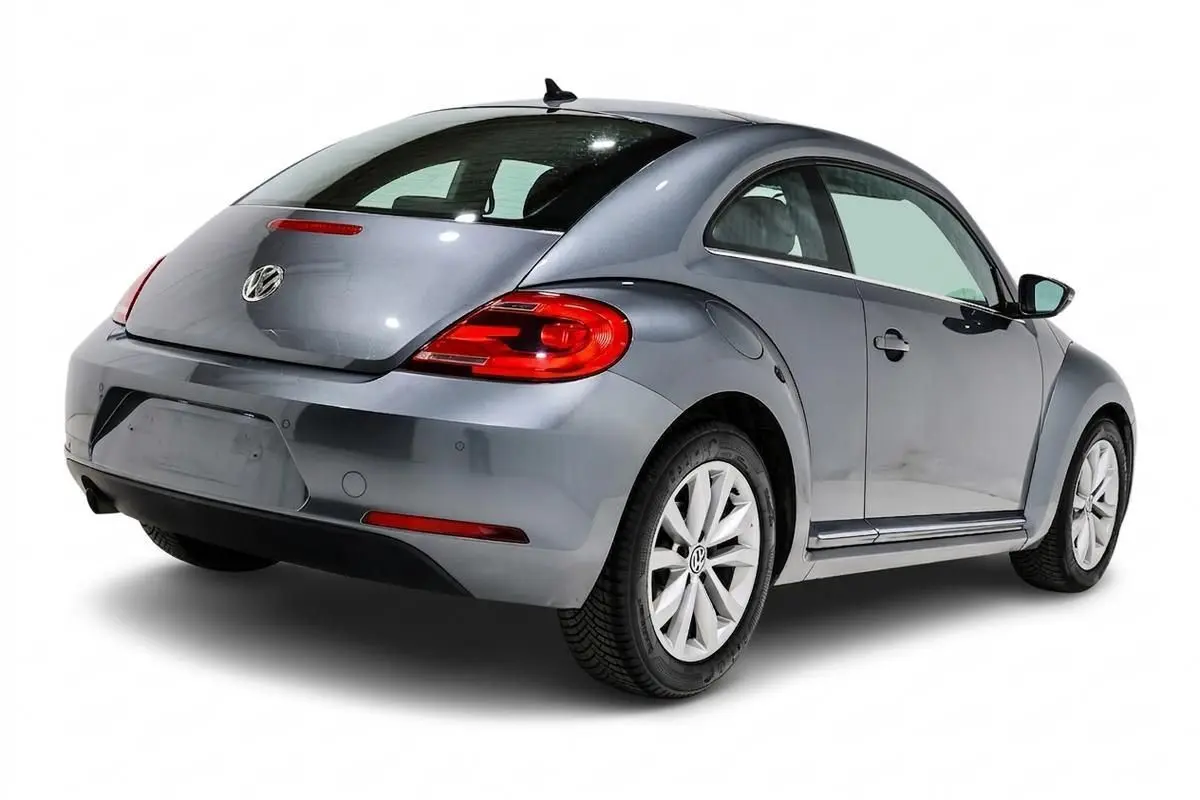 Vue 3/4 arrière droite d'une Volkswagen Coccinelle gris métallisé avec feux arrière rouges et jantes alliage.