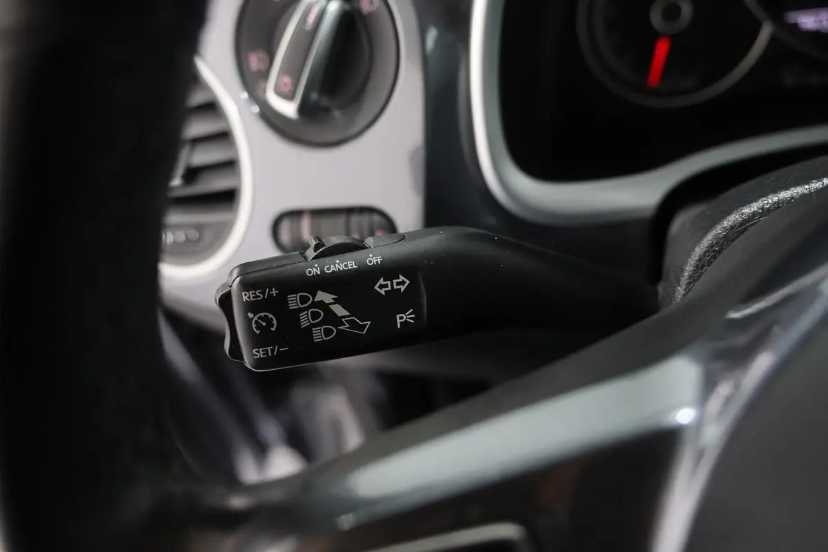 Gros plan sur la commande de régulateur de vitesse à gauche du volant dans une Volkswagen Coccinelle gris 2016.