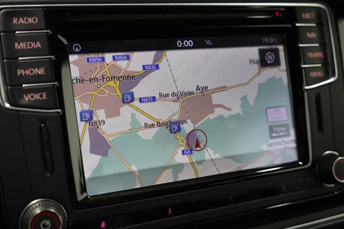 Gros plan sur l’écran GPS intégré au tableau de bord du Volkswagen Coccinelle gris, affichant une carte routière.