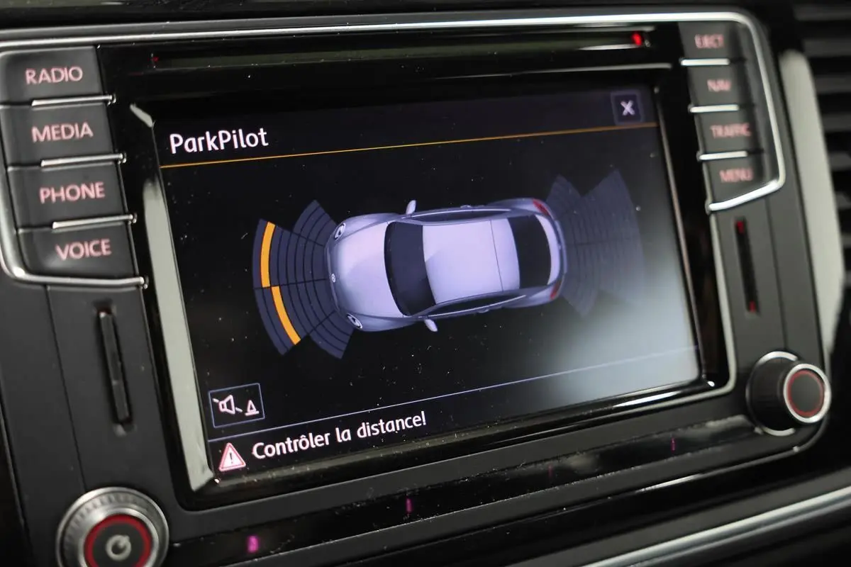 Écran central du tableau de bord montrant l'interface ParkPilot avec la silhouette grise de la Volkswagen Coccinelle en vue de dessus.