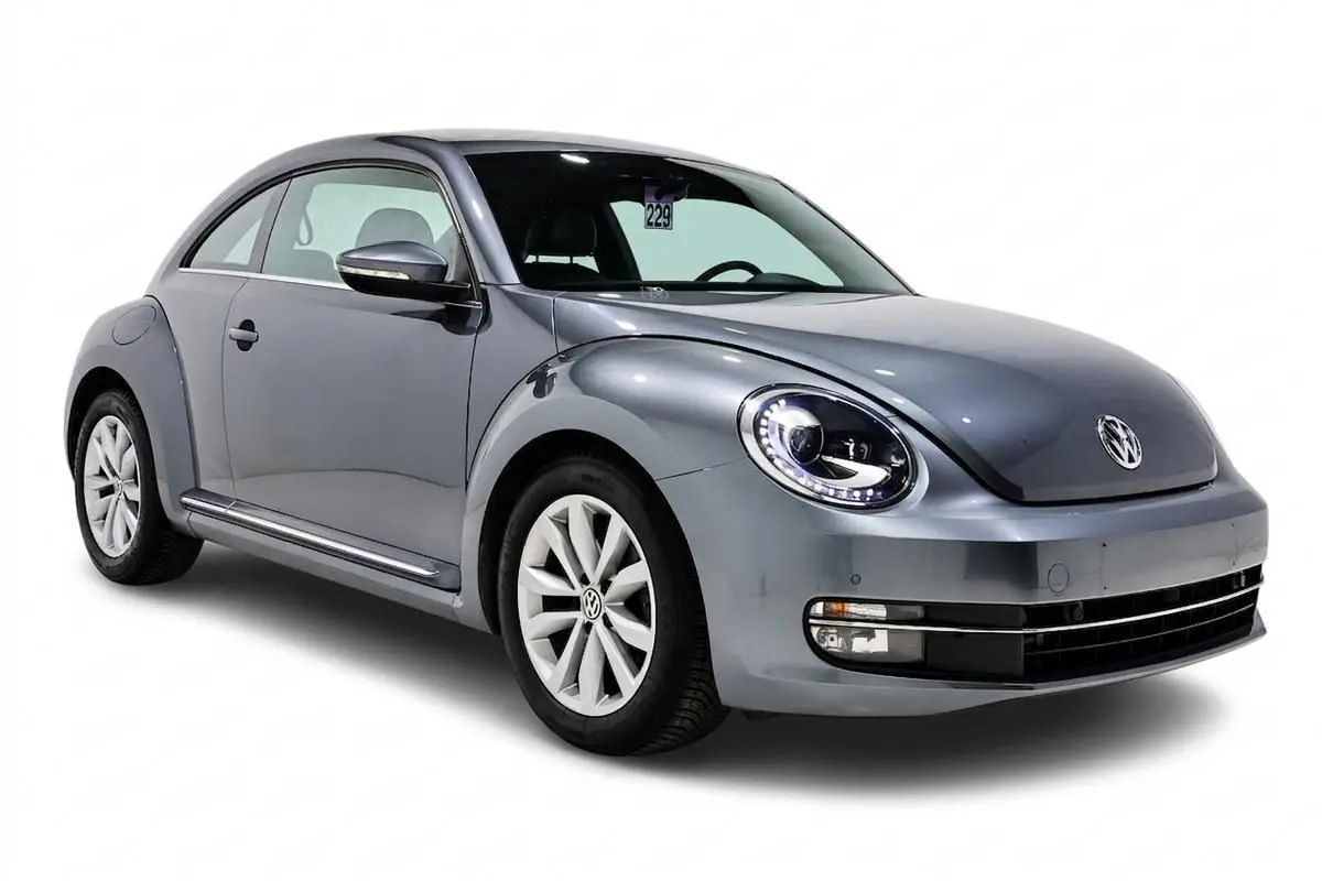 Vue 3/4 avant gauche d'une Volkswagen Coccinelle gris métallisé avec phares LED et jantes alliage.