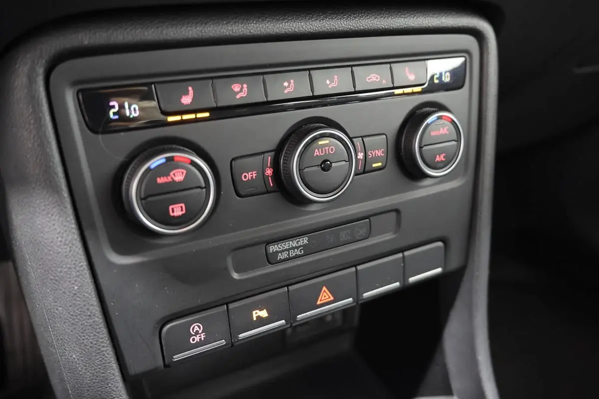 Gros plan sur la console centrale de la Volkswagen Coccinelle 2016, montrant les commandes de climatisation et les boutons de fonction.