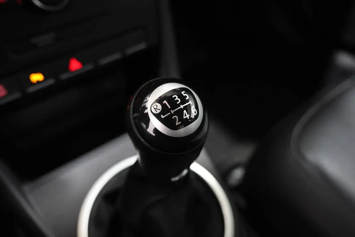 Le levier de vitesse manuel noir de la Volkswagen Coccinelle 1.2 TFSI 105, vue rapprochée de l'intérieur.