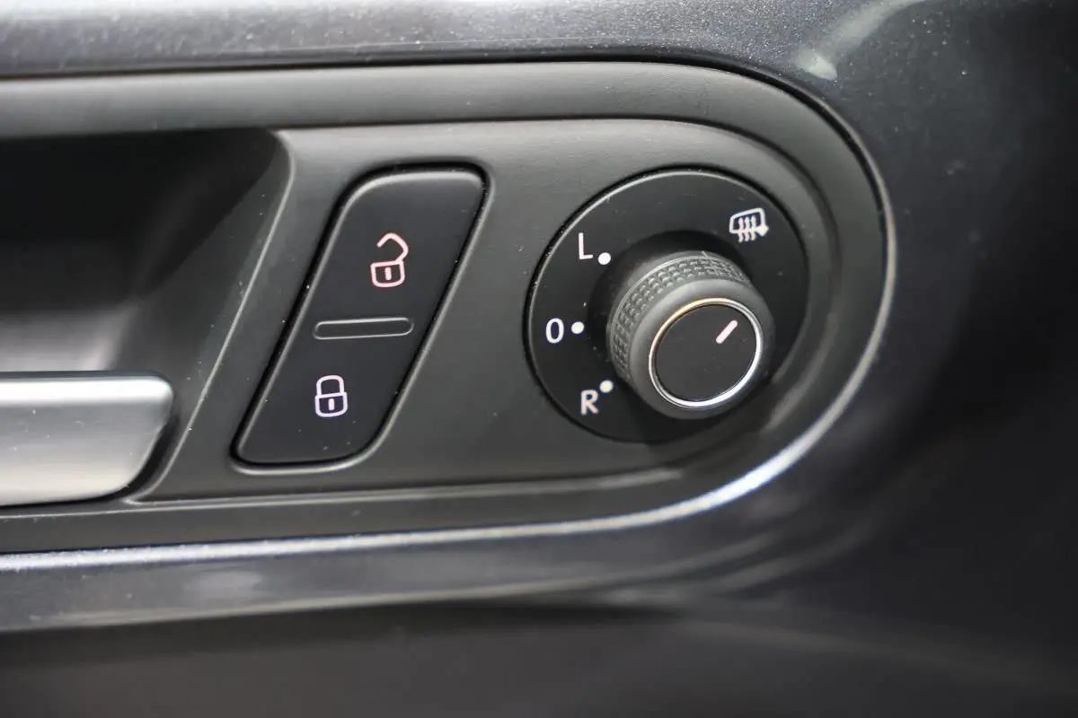Gros plan sur les commandes de réglage des rétroviseurs et verrouillage sur la porte intérieure d'une Volkswagen Coccinelle grise.