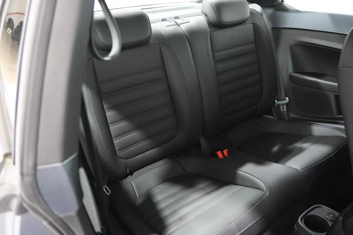 Vue intérieure des sièges arrière en cuir noir de la Volkswagen Coccinelle gris 2016, avec ceinture de sécurité visible.