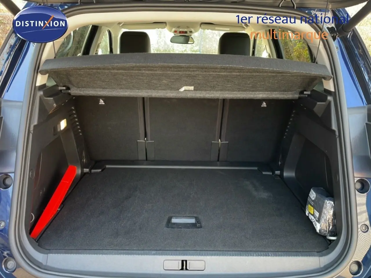 Coffre ouvert vu de l'arrière d'un Citroën C5 Aircross bleu Eclipse Metal, montrant l'espace de chargement et la tablette cache-bagages.