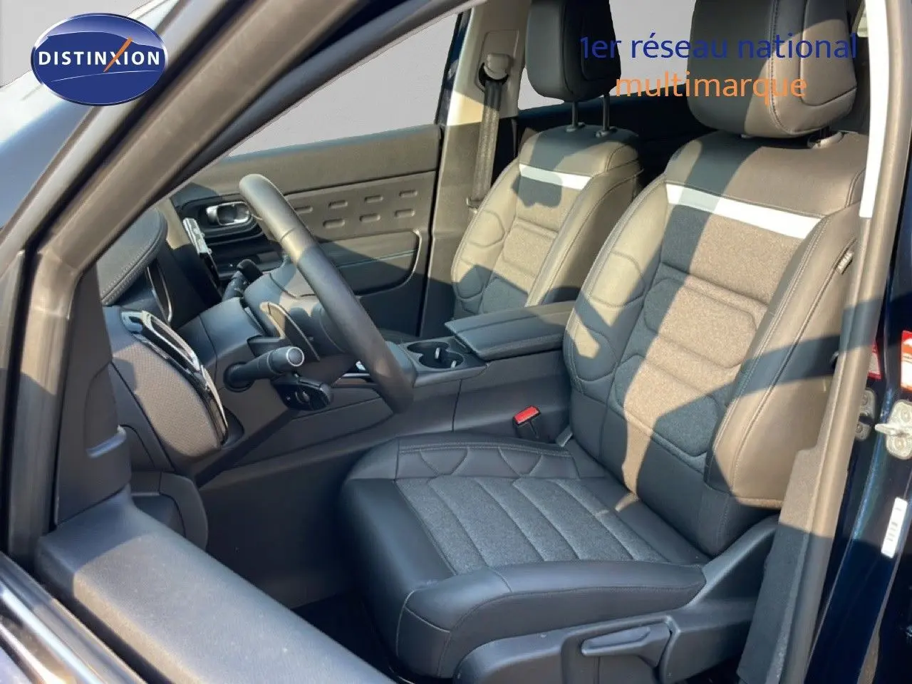 Vue intérieure côté conducteur du Citroën C5 Aircross 2025 bleu Eclipse Metal, sièges tissu et cuir noir avec console centrale.