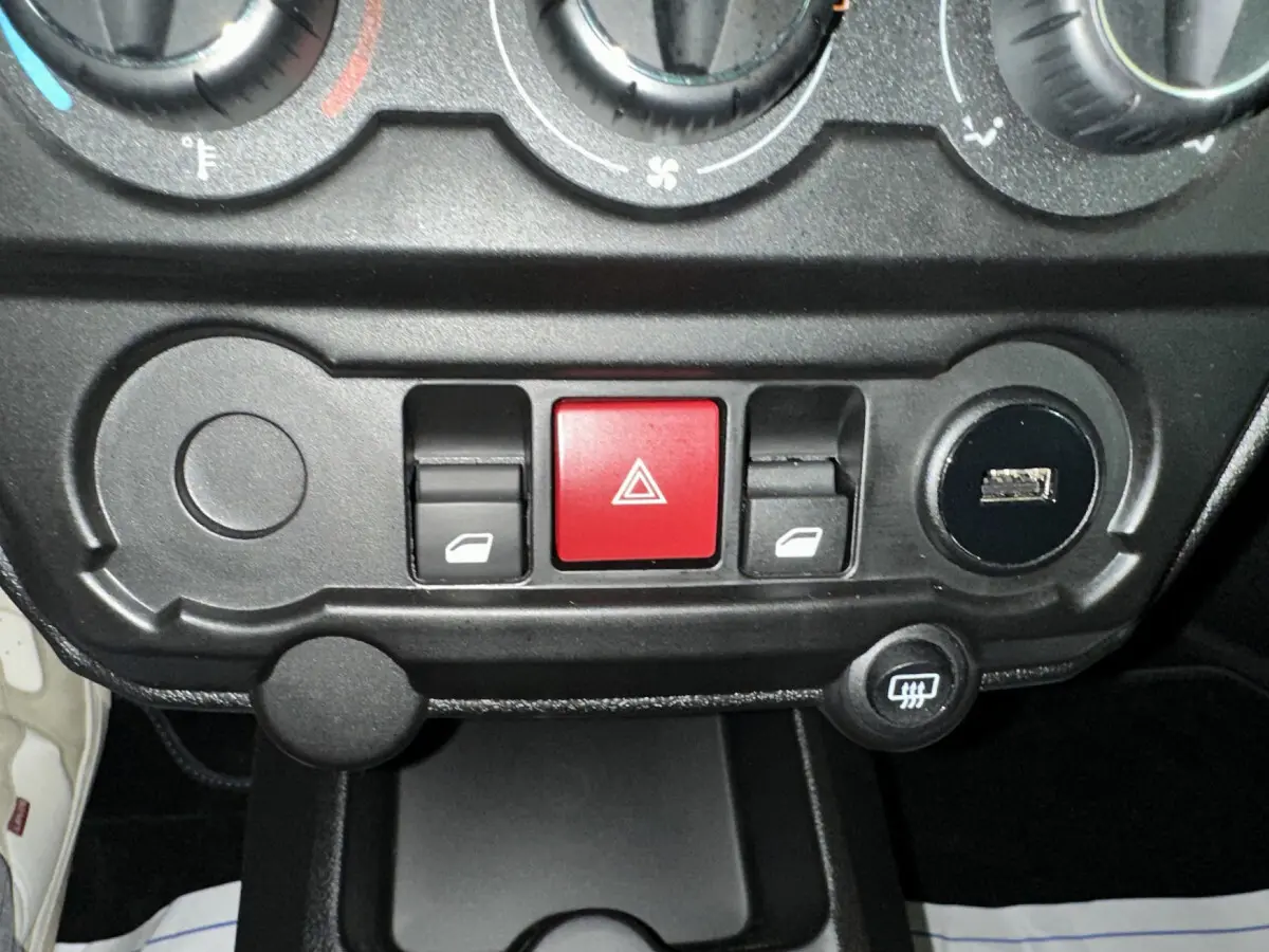 Panneau de commandes intérieur de l'AIXAM AMBITION rouge 2026, avec boutons de vitres électriques et alerte au centre.