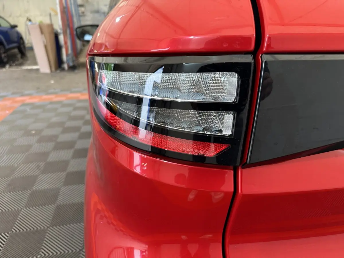 Gros plan sur le feu arrière gauche rouge brillant de l'AIXAM AMBITION 0.5 CITY COUPE GTI E5+ 2026 avec bande noire.