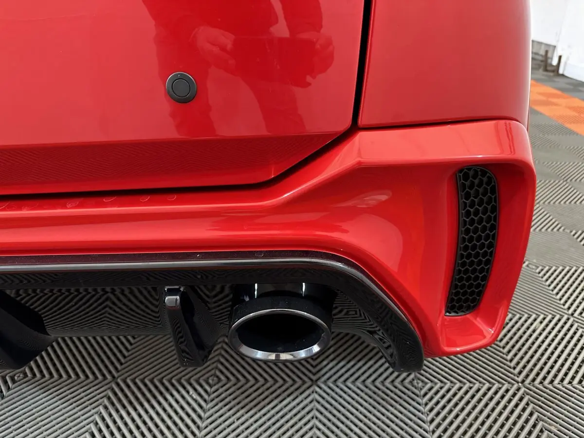 Gros plan sur l'arrière droit rouge d'une Aixam Ambition 0.5 City Coupe GTI 2026 avec sortie d'échappement et diffuseur noir.