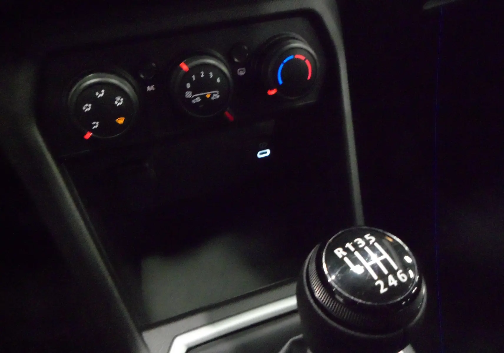 Gros plan sur la commande de la boîte manuelle 6 vitesses du Dacia Jogger 2025, avec les réglages de climatisation en arrière-plan.